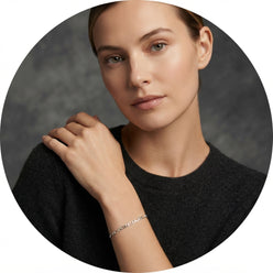 Clara V. wearing a sterling silver Figaro link anklet as a bracelet, set against a modern charcoal and cream studio backgroun