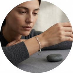 A portrait of influencer Elena Rossi wearing a 925 sterling silver Figaro link anklet as a bracelet against a neutral backgro