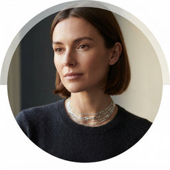 Circular portrait of Lydia Thorne wearing a delicate sterling silver Figaro chain necklace against a neutral charcoal backgro