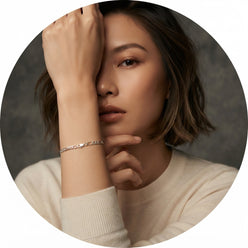 Portrait of influencer Ivy W. wearing a polished sterling silver Figaro link chain on her wrist against a minimalist studio b